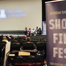 A cinema screen in the background with the audience and a banner for the Short Film Festival in the foreground.
